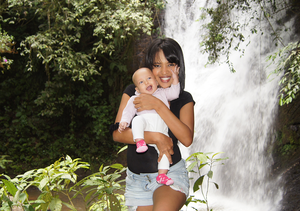 Colombian mom holding baby in front of  waterfall