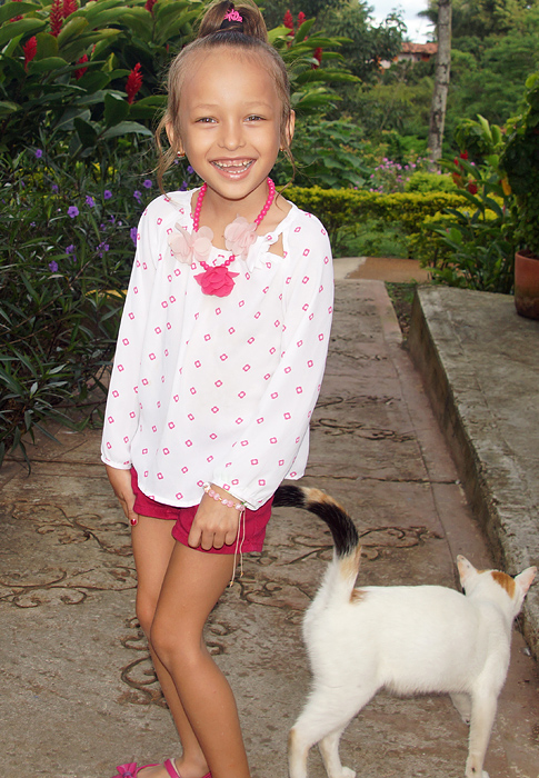 A white cat tickling the legs of a laughing little girl